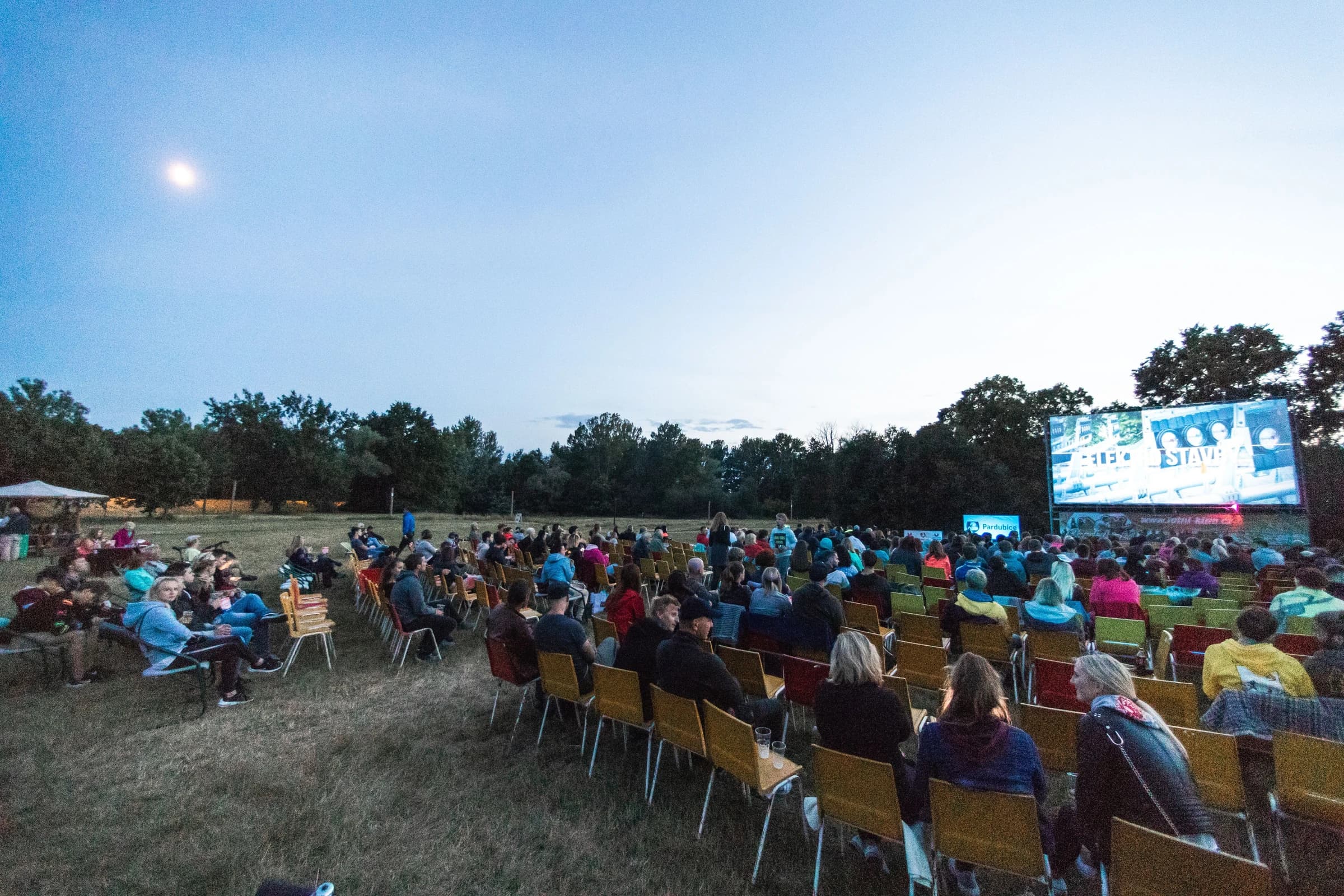 Giant outdoor screen playing for an audience at dusk